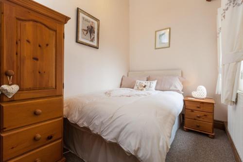 a bedroom with a white bed and a wooden dresser at Skipbridge Farm Cottages in Green Hammerton