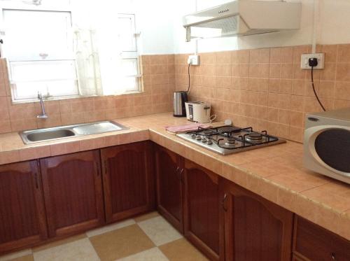 a kitchen with a stove and a sink and a microwave at Ebrahim Flats - Grand Baie Beach in Grand Baie