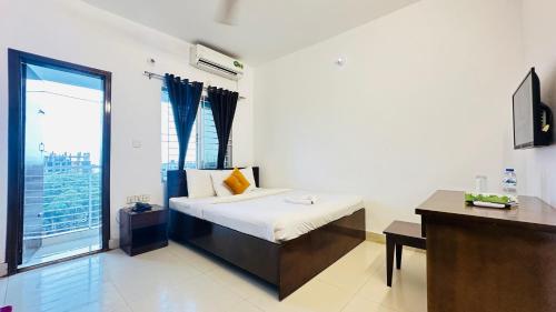 a bedroom with a bed and a desk and a window at Falcon Beach Resort in Cox's Bazar