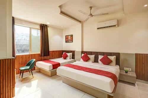 a hotel room with two beds and a chair at Hotel Sai Deluxe in New Delhi