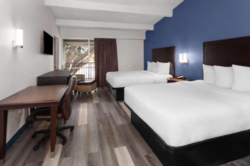 a hotel room with two beds and a desk at Travelodge by Wyndham Milwaukee in Milwaukee
