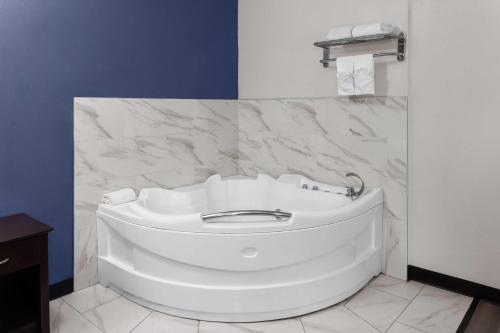 a white tub in a bathroom with a marble wall at Travelodge by Wyndham Milwaukee in Milwaukee