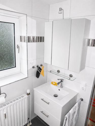 a white bathroom with a sink and a mirror at Carmen u. Rudolf Lutz in Norddeich