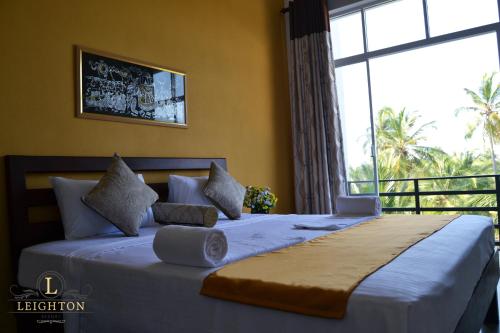 a bedroom with a large bed with a large window at Leighton Resort in Negombo