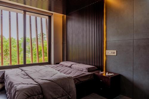 a bedroom with a bed and a large window at E7 Apartment in Bekal