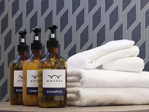 three bottles of shampoo and towels next to towels at Wander Kyoto Nanajo in Kyoto