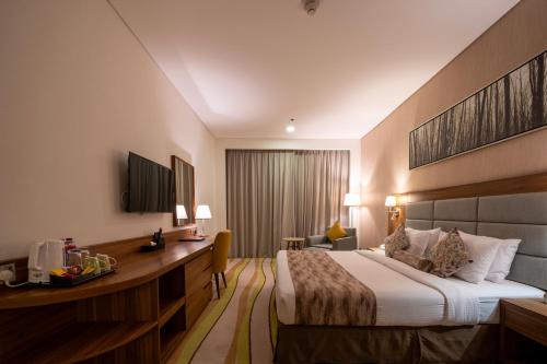 a hotel room with a bed and a desk at Jacob's Garden Hotel in Dubai