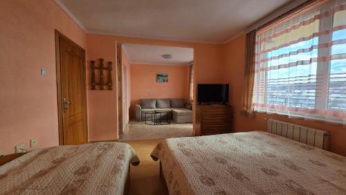 a bedroom with two beds and a living room at Къща за гости МЕЛИСА in Borino