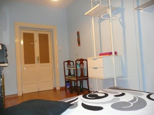 Habitación con cama, 2 sillas y vestidor. en Hostal Loyola, en Madrid