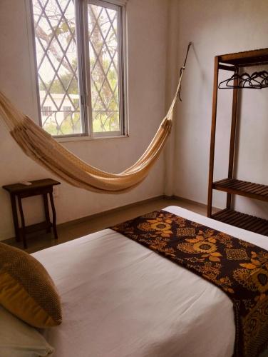 a bed with a hammock in a room with a window at Casa Imox in Bacalar