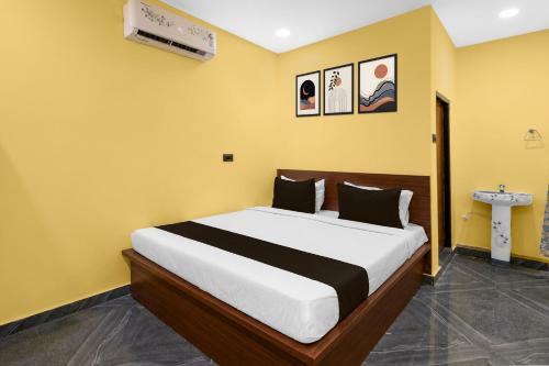 a bedroom with a large bed in a yellow room at Hotel O Shadnagar Formerly Sri Jogulamba Residency in Bālānagar
