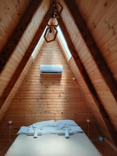 a bed in a wooden room with a window at A-frame с видом на горы in Kokotauri
