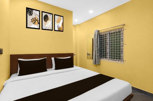 a bedroom with a bed with yellow walls and a window at Hotel O Shadnagar Formerly Sri Jogulamba Residency in Bālānagar