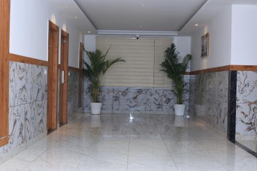 a hallway with potted plants in a building at Hotel New JMK in Katra
