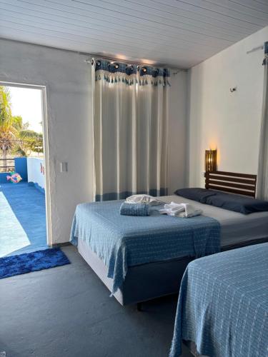 a bedroom with two beds and a door to a patio at Casa Cochilo na Rede in Beberibe