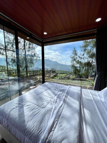 a bed in a room with a large window at Kayana Capsul Dieng in Kejajar