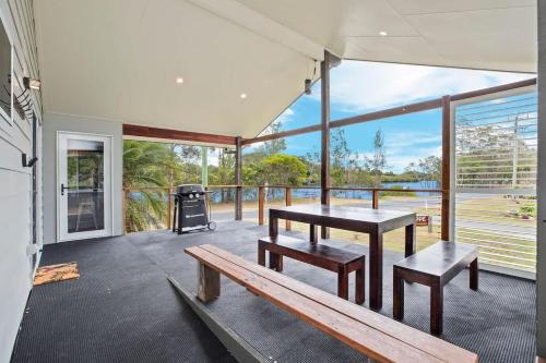 a porch with a bench and a table and a grill at The Palm Cabin 2 in Mylestom