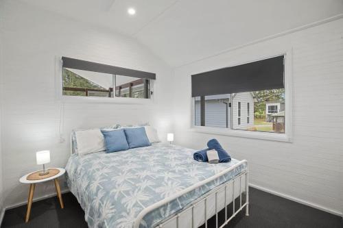 a bedroom with a bed with blue pillows and a window at The Palm Cabin 2 in Mylestom