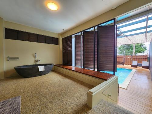 a bathroom with a tub and a swimming pool at Sand & Sandals Desaru Beach Resort & Spa in Desaru