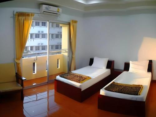 two beds sitting in a room with a window at Chanthanee Hotel in Ban Chamun (2)