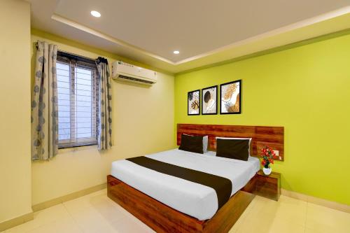 a bedroom with a large bed with yellow walls at Super Hotel O AMR Planet Mall Hyderabad Formerly R Square in Maula Ali