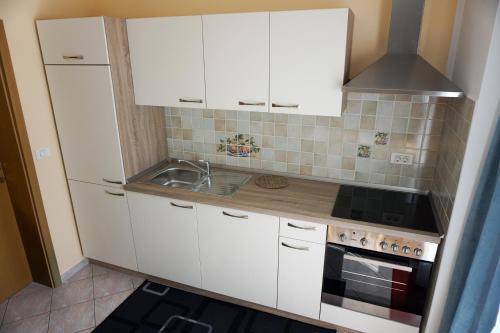 a kitchen with white cabinets and a sink at Apartments Kravanja in Bovec