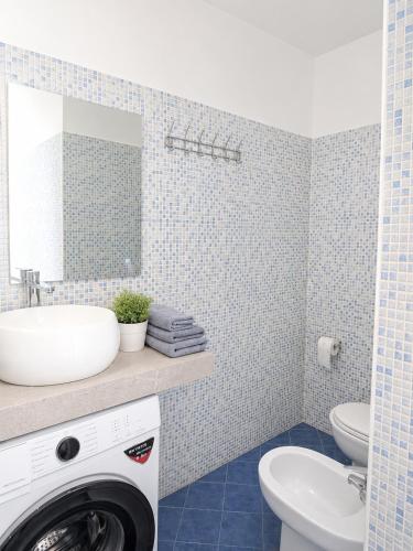a bathroom with a washing machine and a sink at La Splaza Home in Pian Camuno