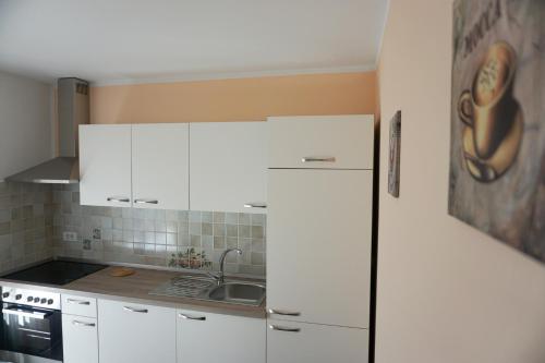 a kitchen with white cabinets and a sink at Apartments Kravanja in Bovec