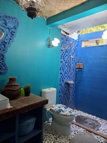 a blue bathroom with a toilet and a blue wall at Bleu Verde, The Self Healing Hotel & Retreat in Gili Trawangan