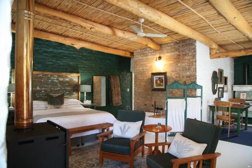 a bedroom with a bed and a table and chairs at Dennehof Karoo Guesthouse in Prince Albert