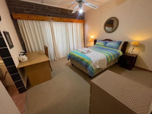 a bedroom with a bed and a table and a window at Eagle Waters in Vanderkloof