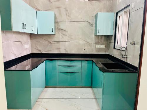 a kitchen with blue cabinets and a sink at Selfie Residency in Mysore