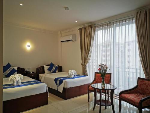 a hotel room with two beds and a table and chairs at Jun Yue Hotel in Phnom Penh