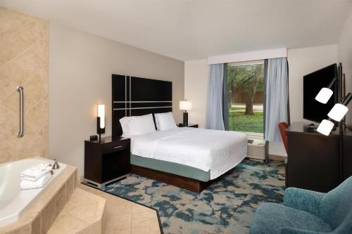 a bedroom with a bed and a tub and a bed and a sink at Hampton Inn Austin Oak Hill in Austin