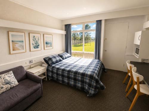 a bedroom with a bed and a couch and a window at Peninsula Motor Inn in Tyabb
