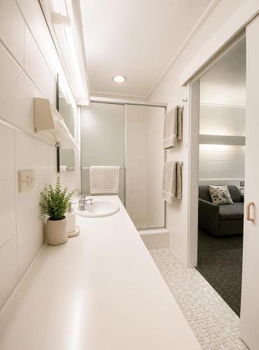 a white bathroom with a sink and a mirror at Peninsula Motor Inn in Tyabb