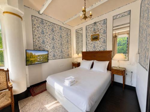 a bedroom with a large white bed with blue wallpaper at Domaine de la Jasseix in Croze