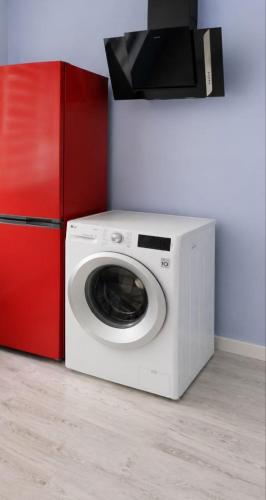 a white washing machine next to a red refrigerator at Kвартира -студия in Daugavpils