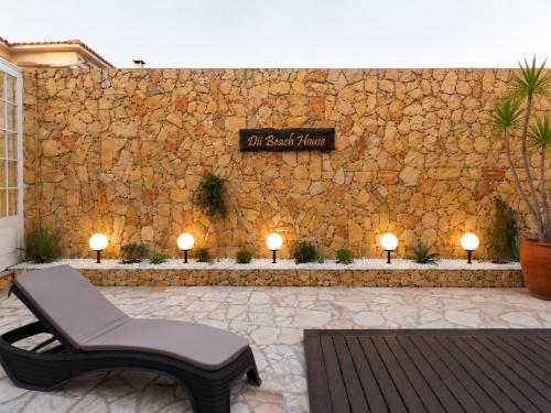 a bench sitting in front of a stone wall at Dii Beach House - Piscina Aquecida 28º-32º C in Torres Vedras