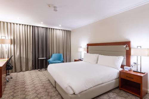 a hotel room with a bed and a blue chair at Holiday Inn - Johannesburg Sunnyside Park by IHG in Johannesburg