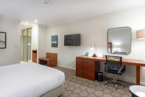 a bedroom with a bed and a desk and a mirror at Holiday Inn - Johannesburg Sunnyside Park by IHG in Johannesburg
