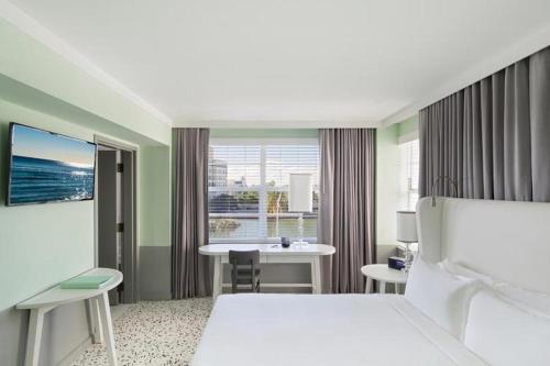 a hotel room with a bed and a table and a window at COMO Metropolitan Miami Beach in Miami Beach