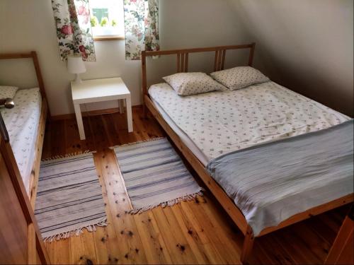 two twin beds in a bedroom with rugs on the floor at Skrawek Nieba in Dąbki