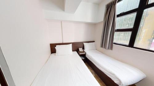 a small room with two beds and a window at Metroplace Olympic in Hong Kong