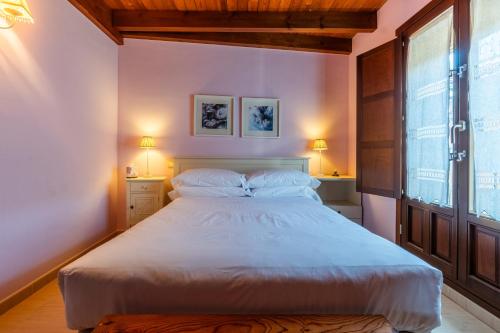 a bedroom with a large white bed with two windows at Casa PETRONILA in Lerma
