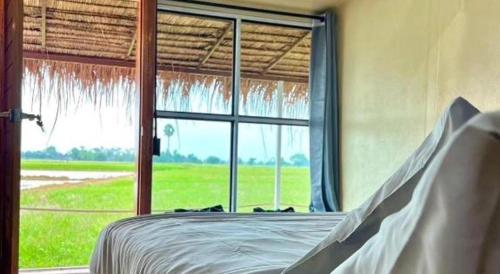 a bedroom with a bed and a large window at The State Resort in Ban Wat Phrik (1)