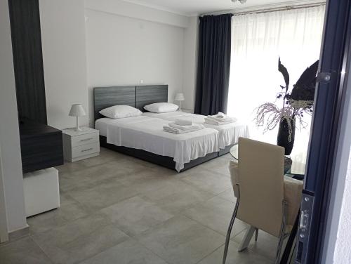 a white bedroom with a bed and a table and chairs at Alivka Apartments in Apolpaina