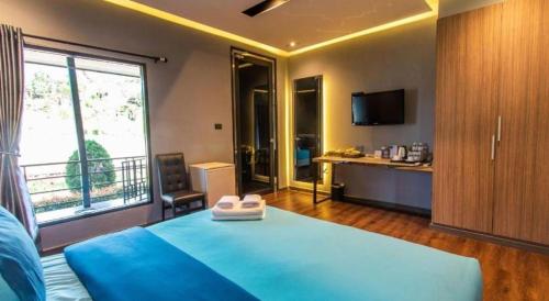 a bedroom with a blue bed and a large window at Mossview Resort in Khao Kho