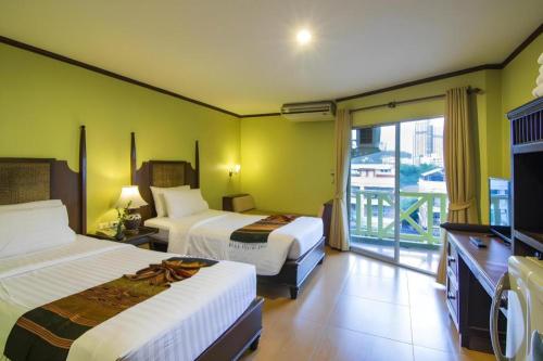 a hotel room with two beds and a balcony at Phuphaya Resort Pattaya in Pattaya South
