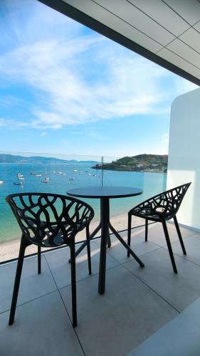a table and chairs on a balcony with a view of the water at Slow Beach Hotel Gran Proa in Raxó